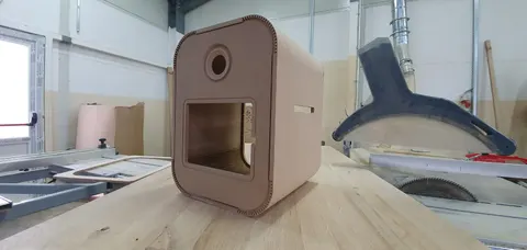 Atelier : la coque en bois brut d’une borne instabox avant la finition, sur l’établi à côté d’une scie