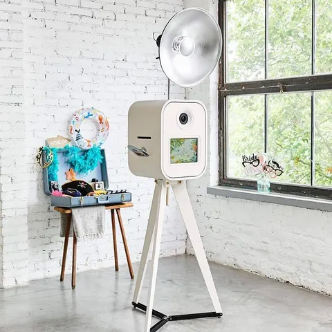 Photobooth blanc avec accessoires dans une salle lumineuse