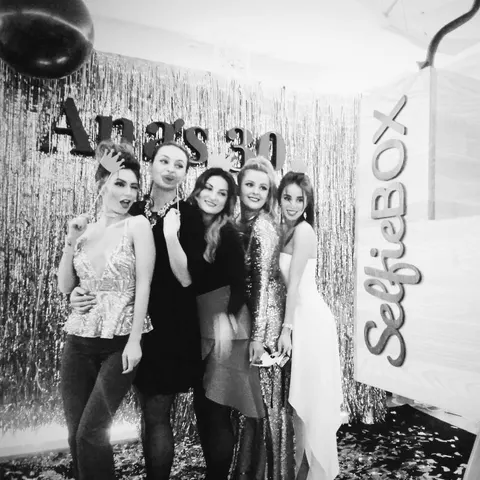 Fotobox-Foto: Schwarz-Weiß-Foto von fünf Frauen in Partykleidern vor glitzerndem Lametta bei einem Geburtstag