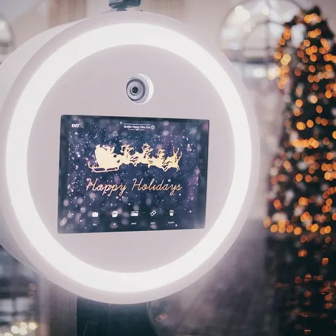 Écran de photobooth affichant un message de fêtes devant des lumières