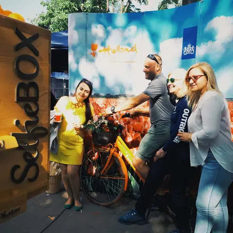 Fotobox-Foto: Vier Personen posieren mit Fahrrad und Tulpen vor einem holländischen Landschaftsdruck im Freien